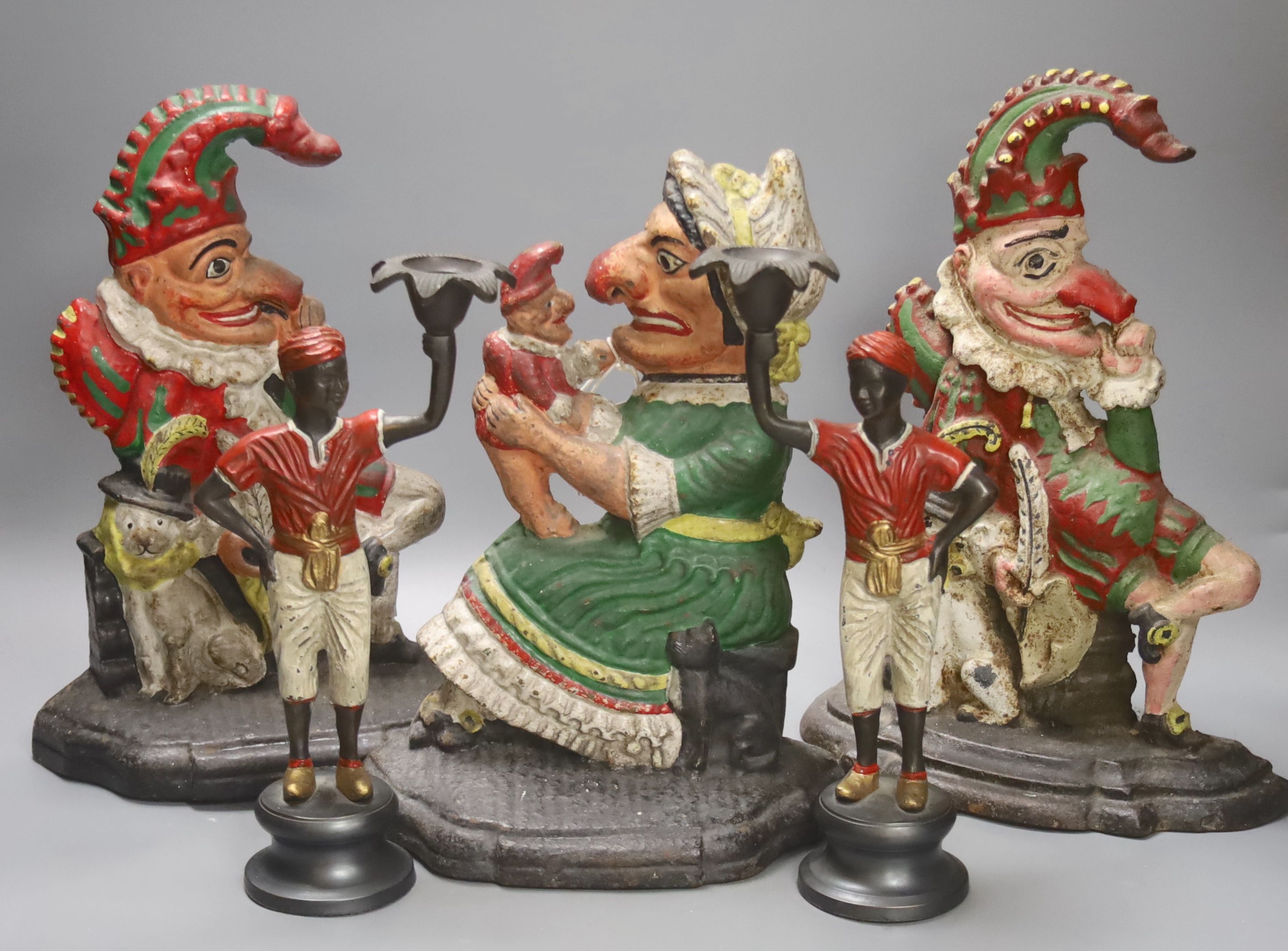 A pair of Victorian cast iron Punch and Judy door stops (later painted), one other and a pair of painted figural cast metal candlesticks, tallest 33cm